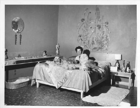 Peggy Guggenheim in her bedroom at Palazzo Venier dei Leoni, behind her the Silver Bedhead made for her by Alexander Calder (1945-46), Venice, early 1950s. (1925, Peggy Guggenheim Collection); Venice, early 1950s. © The Solomon R. Guggenheim Foundation, Photo Archivio CameraphotoEpoche, Gift of Cassa di Risparmio di Venezia, 2005